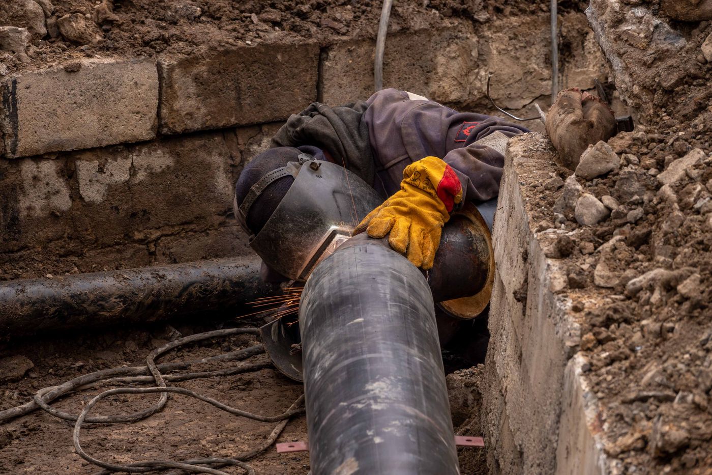 Welder joining a large pipeline in a prepared trench